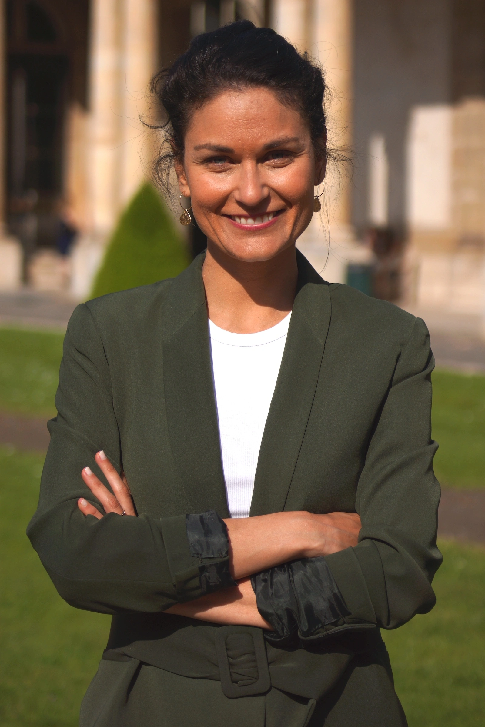 Chloé Sargis souriante en tailleur vert dans un parc parisien